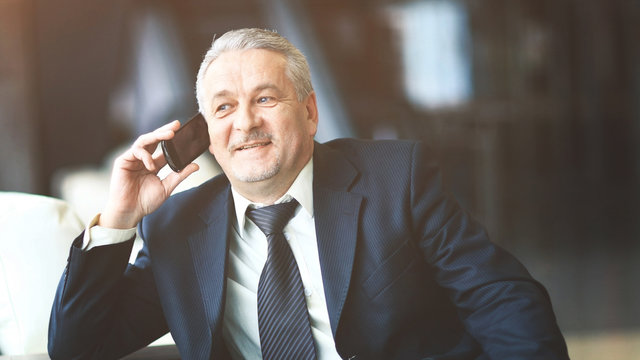 Smiling businessman sitting and talking on the phone