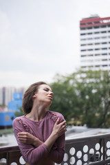 A tall beautiful European woman standing and enjoying the morning sun from her balcony