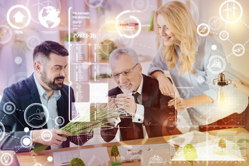 Interesting material. Cheerful friendly landscape designers feeling happy and smiling while touching unusual plants