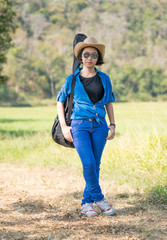 woman wear hat walking and carry her guitar bag