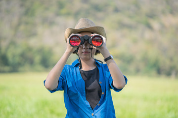 Woman wear hat and hold binocular in grass field