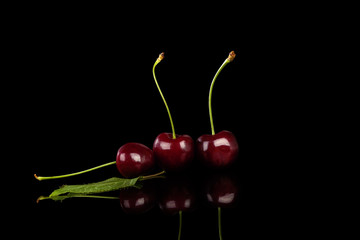 Red ripe cherries on black background.