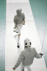 Two young fighters in protective mask fighting at the fencing competition