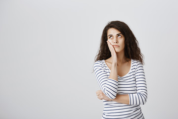 Girl screaming internally from boredom. Cute emotive curly-haired caucasian female making facepalm and rolling eyes from annoyance, hearing nonsense or boring conversation, standing over gray wall