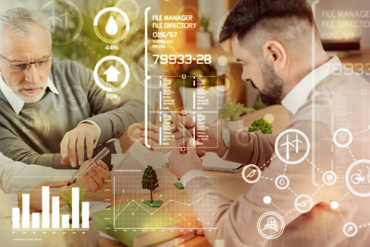 Careful examination. Attentive clever landscape designers looking concentrated while sitting together and comparing various seeds