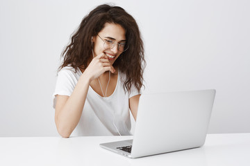 Social network geek chatting with friends. Charming european female with curly hair sitting with...