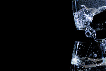 Two inverted transparent glasses with water flowing out of them.	