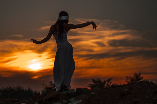 Silhouette of a girl dancing Oriental dance at sunset.