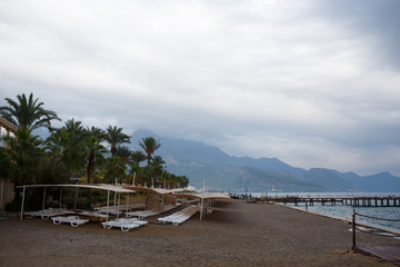 Comfortable sunbed at summer resort beach. Exotic travel destination for summer vacation. Cloudy sky. Turkey, the Mediterranean Sea, view on mountains