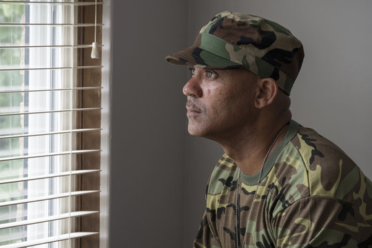 Portrait of a black man in fatigues looking out a window