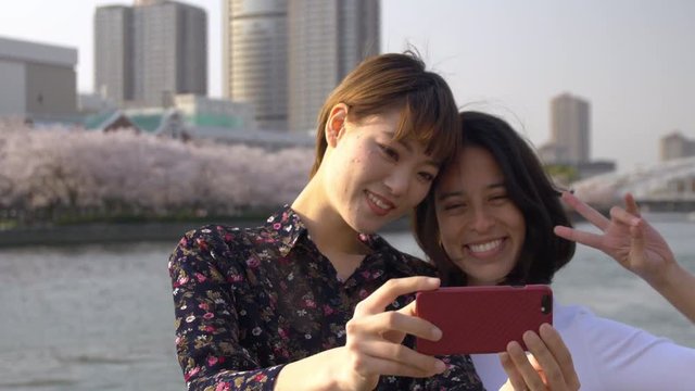 Wonderful women taking selfies by a beautiful river in Japan.