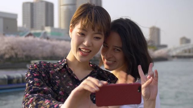 Wonderful women taking selfies by a beautiful river in Japan.