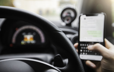 Driver on the phone whilst at the wheel of a car, texting and driving. 