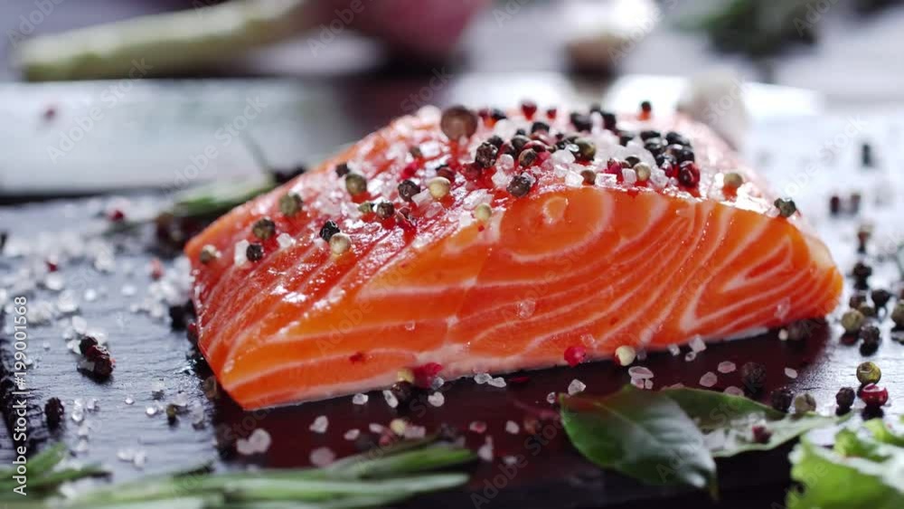 Wall mural Raw salmon steak with spices and herbs. Camera moves around the object. 4K video.