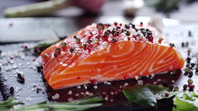 Raw salmon steak with spices and herbs. Camera moves around the object. 4K video.