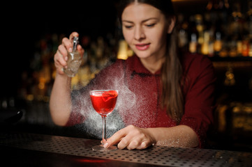 barmaid adds peat whiskey to alcoholic cocktail