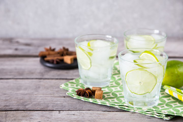 homemade lemonade with lime, anise, cinnamon and ice on a wooden background