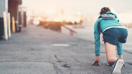 Fit and sporty woman preparing for start in running position