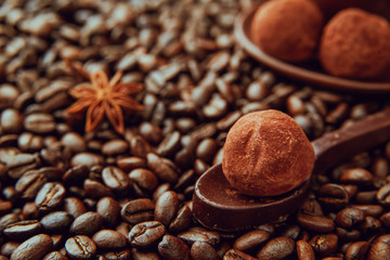 The spoon made of dark chocolate with homemade healthy vegan chocolate truffles lies on the coffee beans.