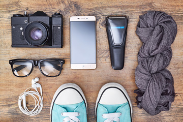 Top view travel or vacation concept. Camera, smartphone, razor, headphones, sneakers, glasses.