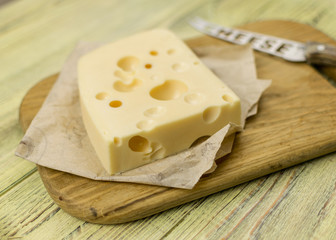 Cheese on cutting board  and knife on wooden background