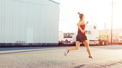 Fit woman jogging in city industrial district