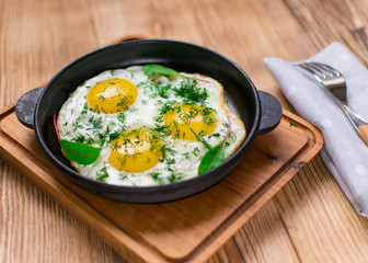 fried eggs in a frying pan and greens.