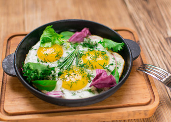 fried eggs in a frying pan and greens.