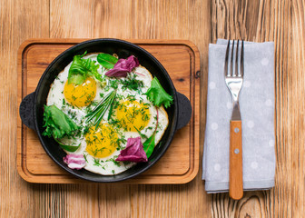 fried eggs in a frying pan and greens.