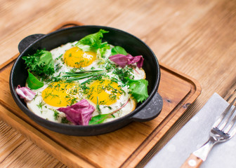 fried eggs in a frying pan and greens.