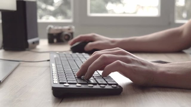 Young man typing on a keyboard and then using mobile phone smartphone and typing a messege. Freelancer photographer working and using tablet for communication with clients.