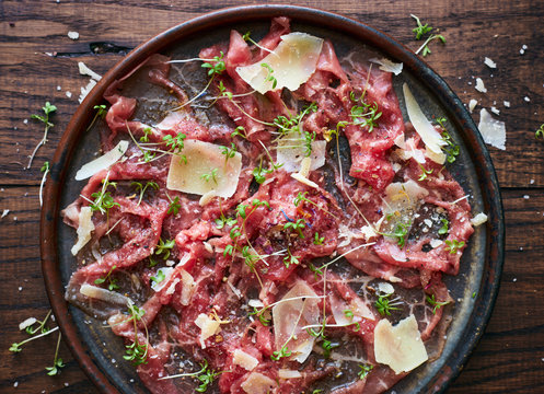 Delicious homemade beef carpaccio with Parmesan cheese spices and herbs top view