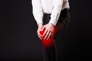 Man with pain in knee on black background