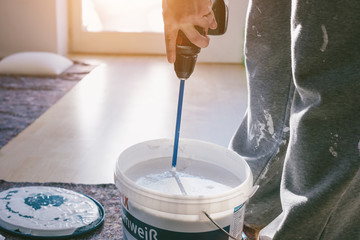Painter working with paint roller and brushes to paint the room