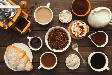 Various coffee cups and sweet pastry on vintage wooden table, top view