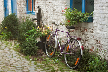 Fototapeta na wymiar Old bicycle on the backyard on the white brick wall background.