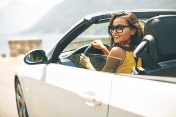 Pretty young woman in white cabriolet car - obrazy, fototapety, plakaty