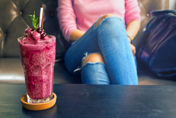 Blueberry smoothie on the table with background women sit on sofa.