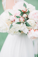 Beauty wedding bouquet of pink and white peony flowers in bride's hands.