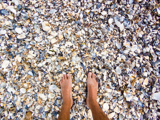 Selfie of man bare feet on seashalls on sea beach, summer concept