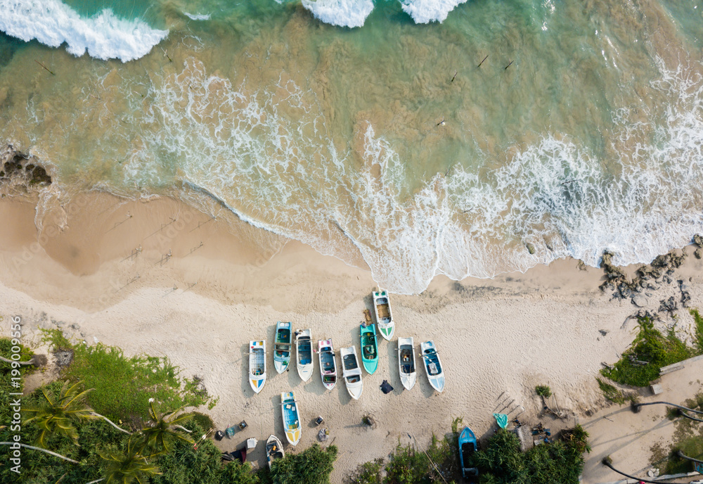 Wall mural beautiful beach with turquoise water and fishing boats on the beach. road on the coast of the ocean.