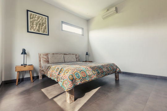 Simple bedroom in villa interior, wooden bed, lamp, white walls,  minimalism