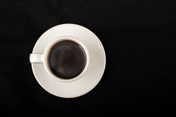 Obraz na płótnie Canvas White cup of coffee on black surface