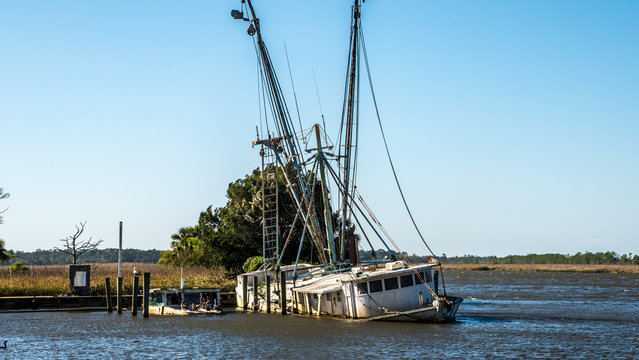 Sunken shrimp boats are still tied to the dock in apalachicola Florida. These boats were abandoned after sinking in a storm or hurricane .
