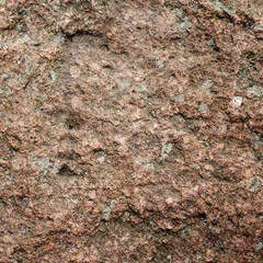 Stone rock with cracks and with a rough surface. Dark brown texture with natural pattern in nature. Square.