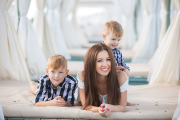 Summer portrait of mother and two son on the beach. Happy family