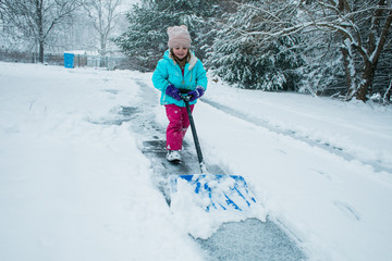 A young girl shoveling snow in a winter storm