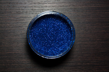 Cobalt blue glitter powder isolated on dark wooden background from a high angle view