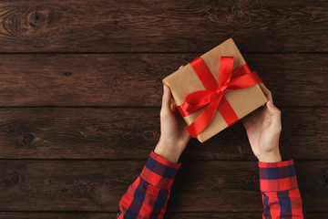 Fototapeta premium Man holding gift in his hands on wooden background