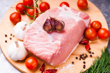 Raw pork on cutting board and vegetables 
